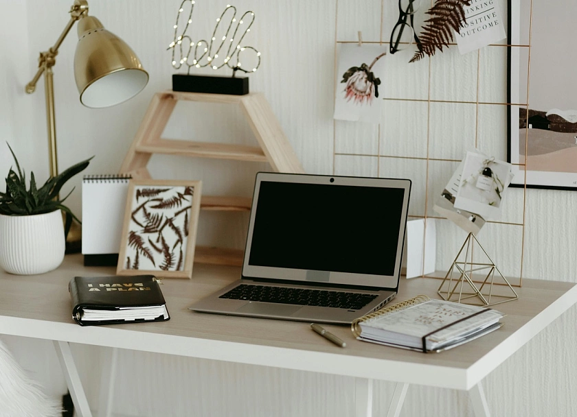 Ein Schreibtisch mit einem Laptop, Notizblöcken und Dekoration