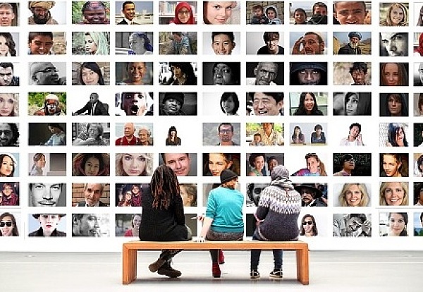 Drei Personen vor einer Wand mit vielen Fotos