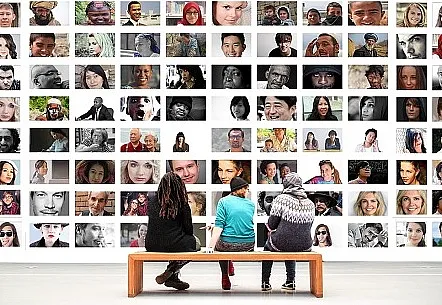 Drei Personen vor einer Wand mit vielen Fotos