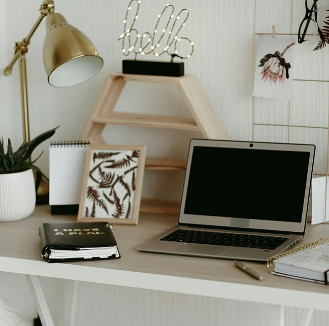 Schreibtisch mit Laptop, Notizblöcken und Dekoration