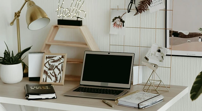 Ein Schreibtisch mit Laptop, Notizbüchern und Dekoration