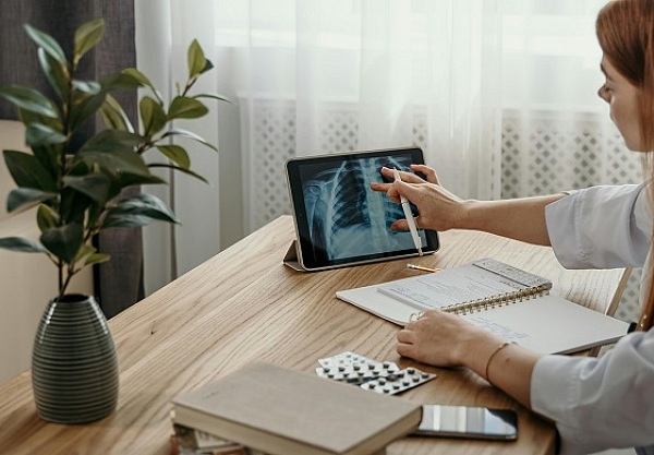 Eine Frau am Tisch, mit Röntgenbild und Notizbuch